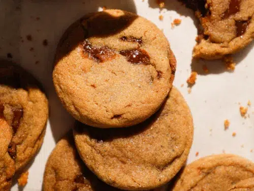Brown butter brown sugar cookies with melted toffee pieces, stacked with coffee cup.