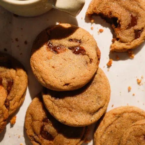 Brown butter brown sugar cookies with melted toffee pieces, stacked with coffee cup.