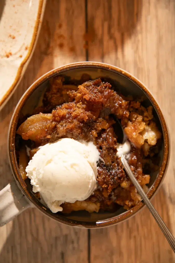 Close-up of gooey apple dump cake topped with melting vanilla ice cream