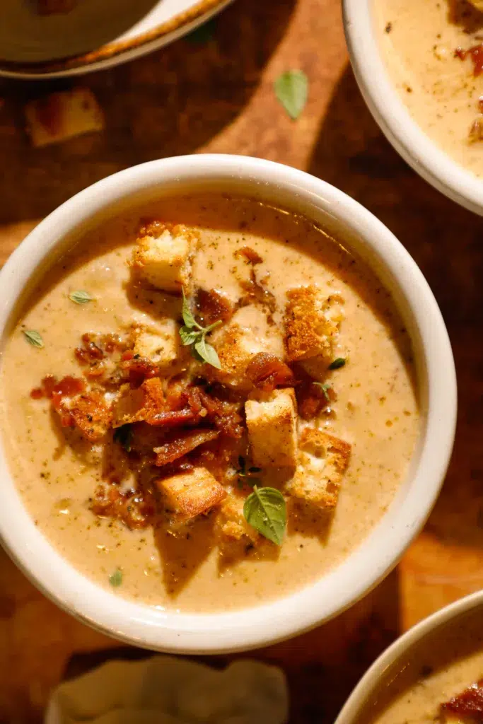 Bowls of creamy cauliflower chowder topped with crispy bacon, golden croutons, and fresh herbs