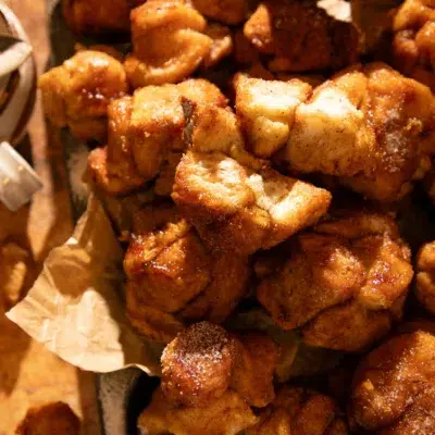 Rustic tray filled with pumpkin spice monkey bread muffins, golden brown and glazed with maple brown butter.