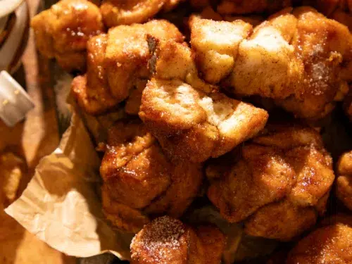 Rustic tray filled with pumpkin spice monkey bread muffins, golden brown and glazed with maple brown butter.
