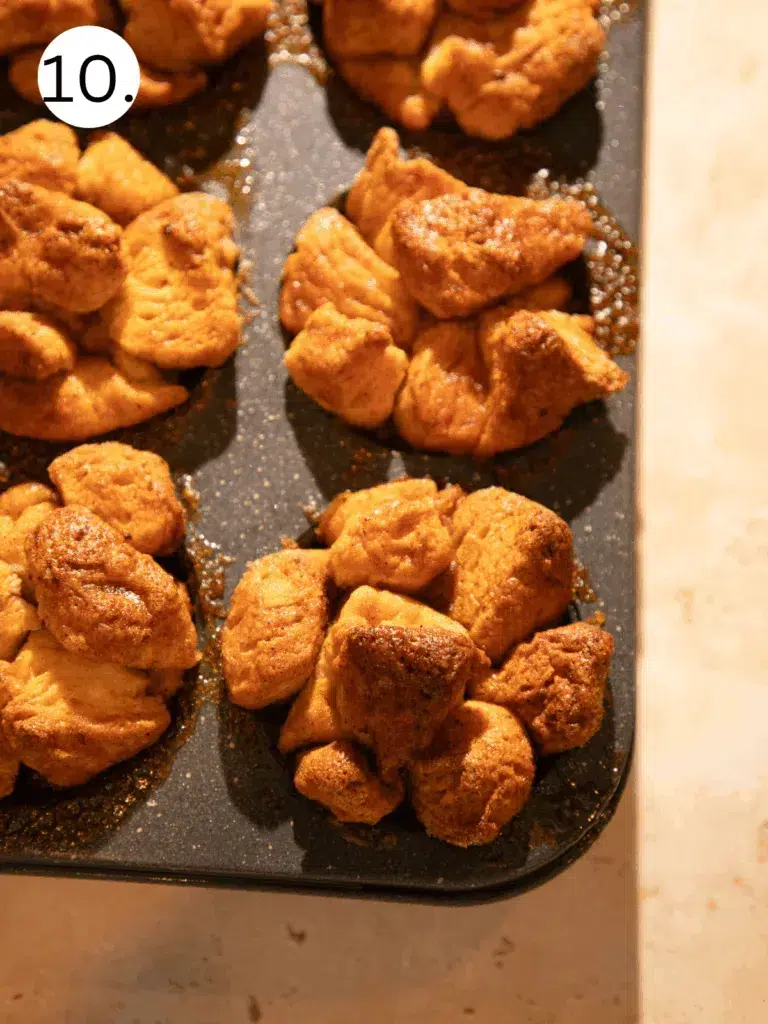 Freshly baked golden brown pumpkin spice monkey bread muffins cooling in muffin tin.