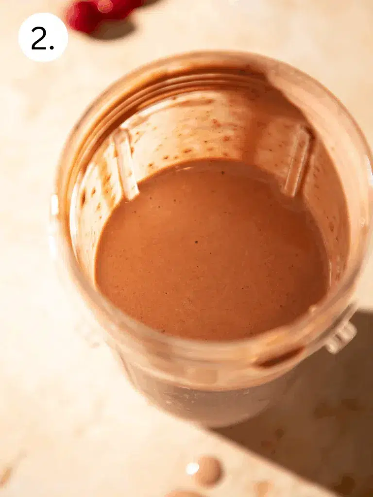 Blended chocolate cherry espresso protein shake in a blender cup with a smooth creamy texture.