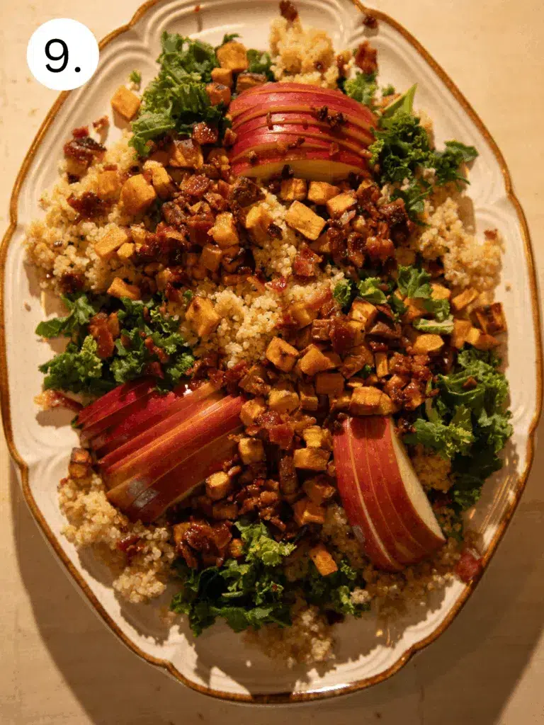 Platter topped with kale, quinoa, roasted sweet potatoes, bacon crumbles, and sliced apples before finishing touches.