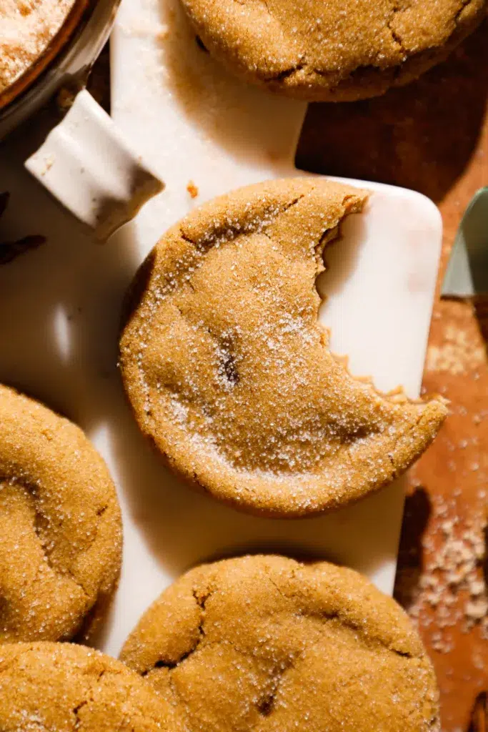 Soft and chewy molasses ginger cookie with a sugar coating and a bite taken out to show the texture.