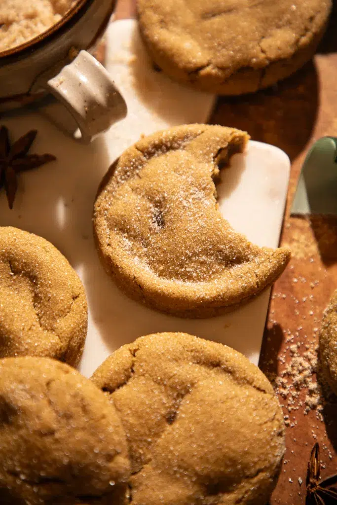 Detailed close-up of a chewy molasses ginger cookie sprinkled with sugar on a marble board.