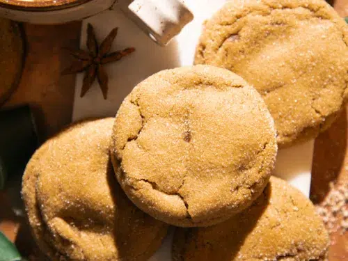 A stack of chewy molasses ginger cookies sprinkled with sugar and styled with star anise for cozy holiday vibes.