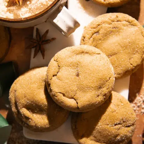A stack of chewy molasses ginger cookies sprinkled with sugar and styled with star anise for cozy holiday vibes.