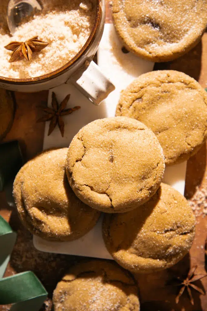 A stack of chewy molasses ginger cookies sprinkled with sugar and styled with star anise for cozy holiday vibes.