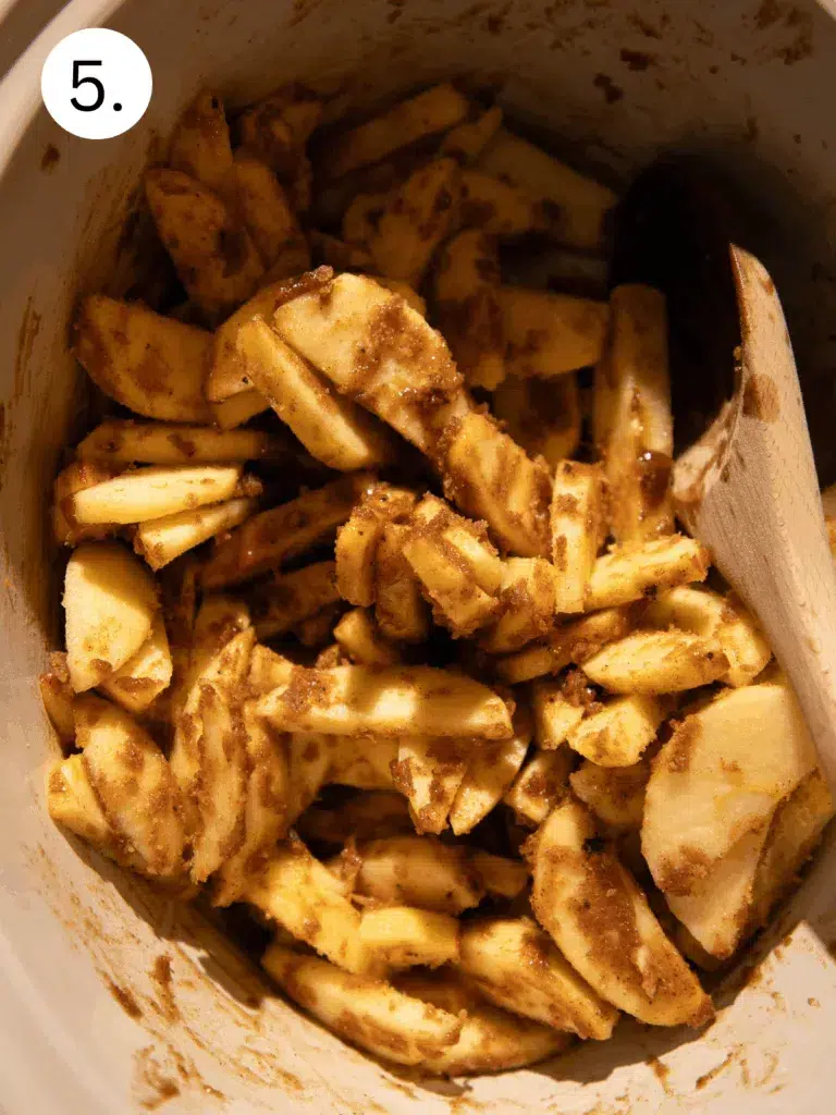Apple slices tossed in brown sugar and cinnamon mixture in crockpot.