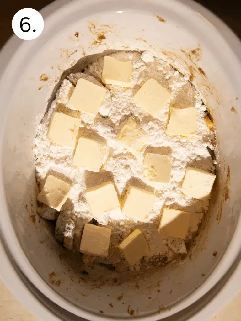 Yellow cake mix and butter slices layered over spiced apples in slow cooker.