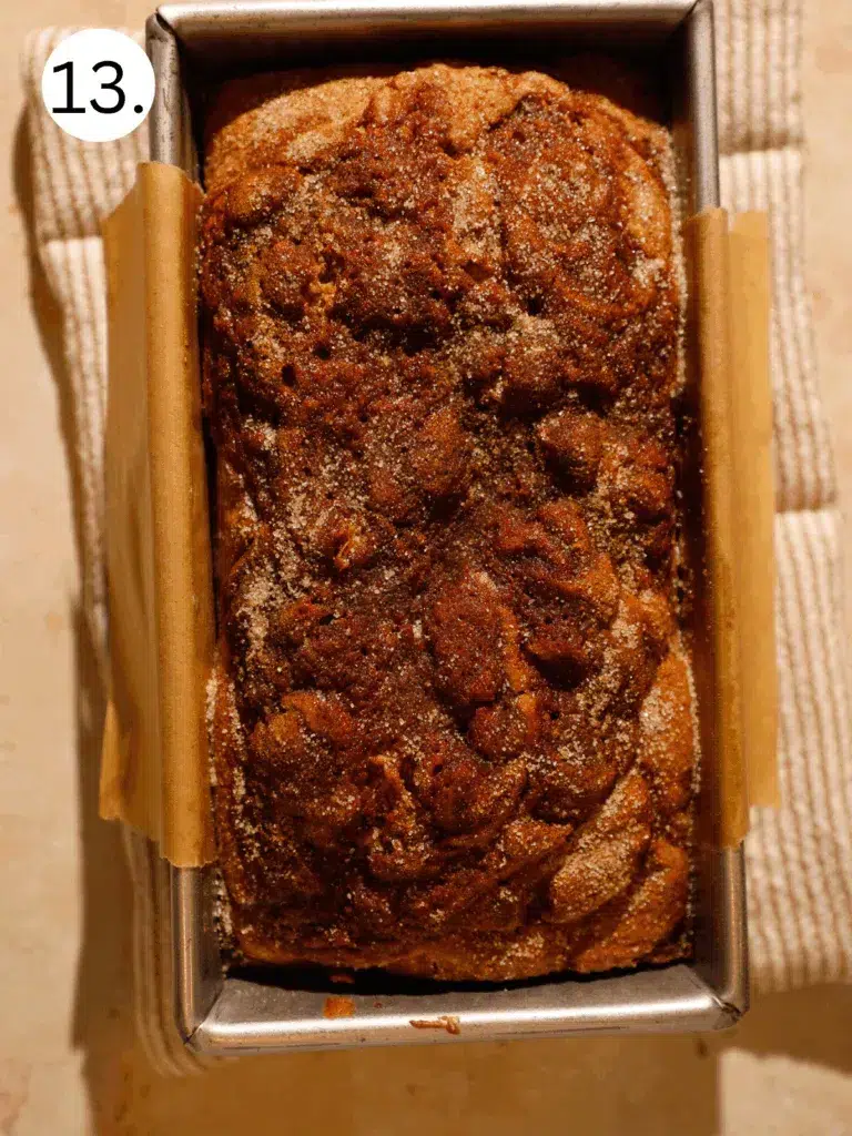 Golden baked caramel apple cider donut bread in loaf pan with cinnamon sugar crust.