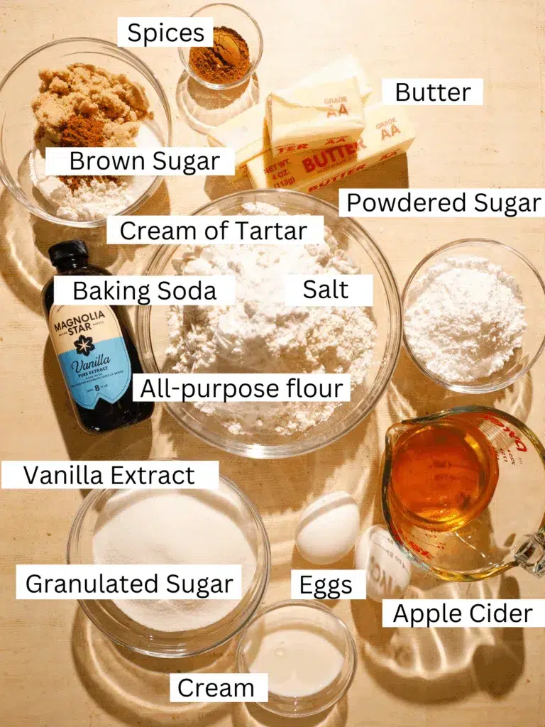 Overhead view of measured baking ingredients for apple cider coffee cake cookies including flour, butter, sugars, apple cider, spices, and eggs.