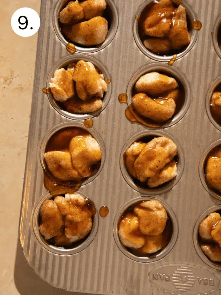 Muffin tin filled with spiced biscuit dough pieces topped with maple brown butter sauce before baking.