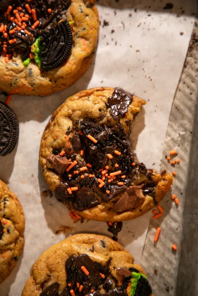 Soft and chewy Halloween chocolate chip cookie with melty chocolate chunks, sprinkles, and a bite missing.