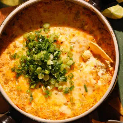 Side view of cheesy baked green chile dip with golden top and fresh green onions.