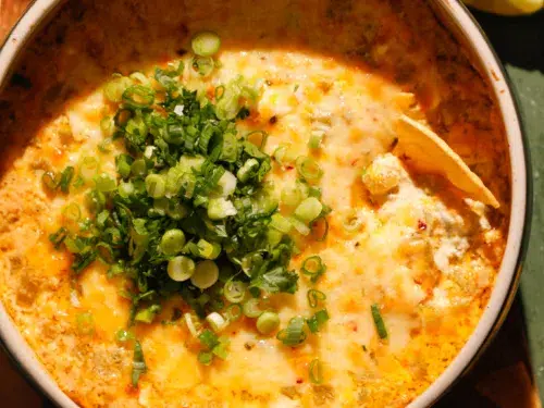 Side view of cheesy baked green chile dip with golden top and fresh green onions.