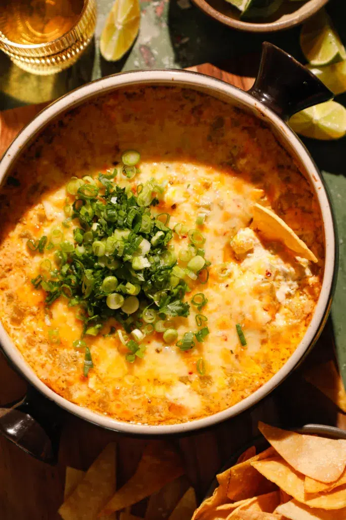 Side view of cheesy baked green chile dip with golden top and fresh green onions.