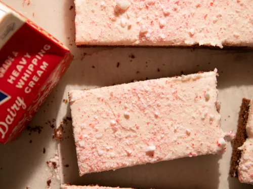 Peppermint mocha cookie bars arranged on a white surface with a carton of heavy cream for a cozy holiday look.