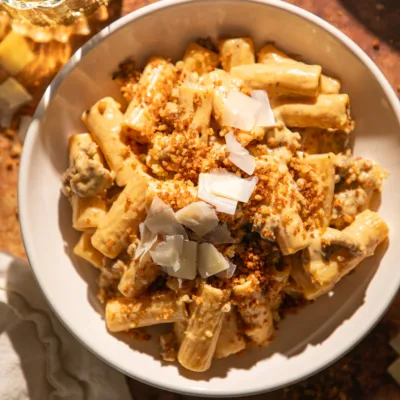Bowl of creamy brown butter pumpkin Alfredo rigatoni topped with crispy breadcrumbs and shaved Parmesan.