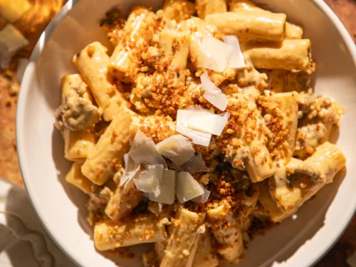 Bowl of creamy brown butter pumpkin Alfredo rigatoni topped with crispy breadcrumbs and shaved Parmesan.