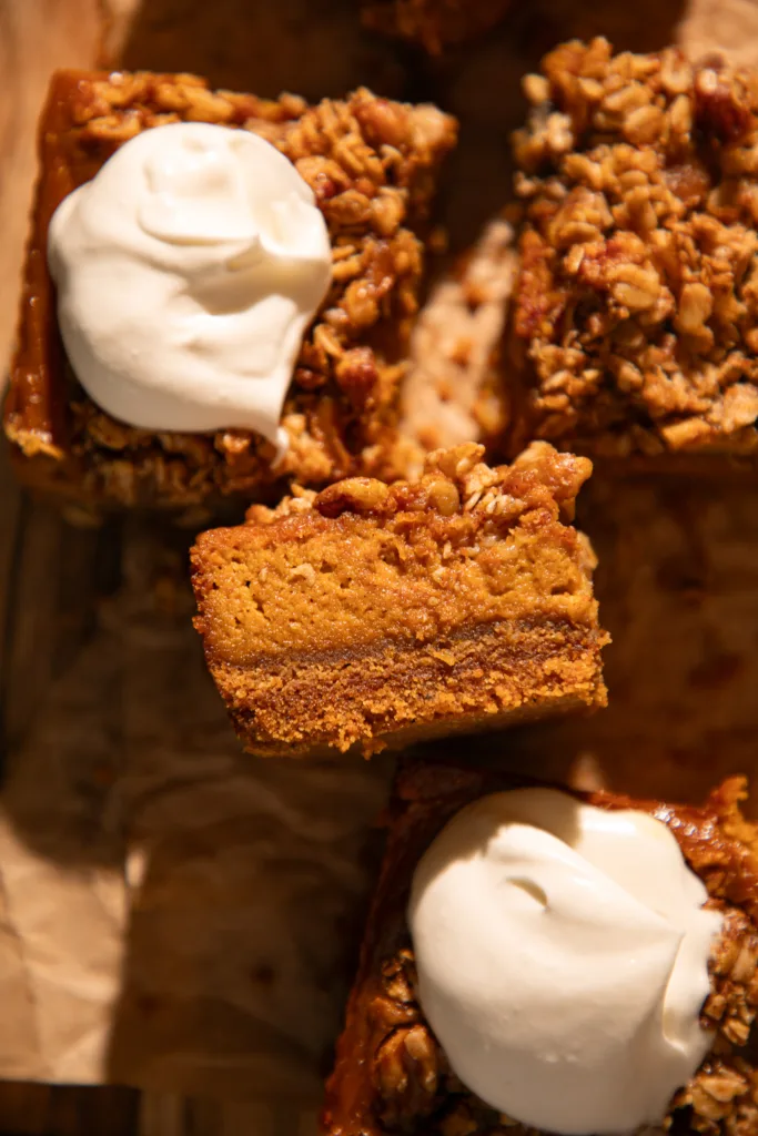 Side view showing layers of graham cracker crust, creamy pumpkin filling, and golden oat streusel topping.