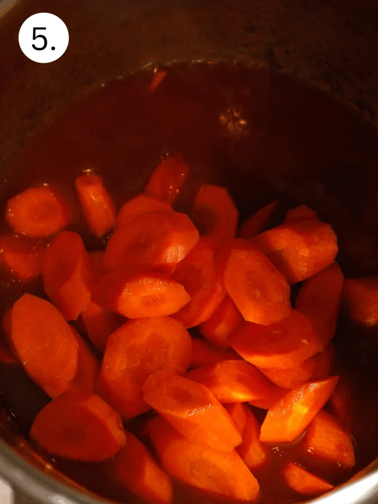 Sliced carrots added into the rich red wine sauce inside the Instant Pot during cooking.