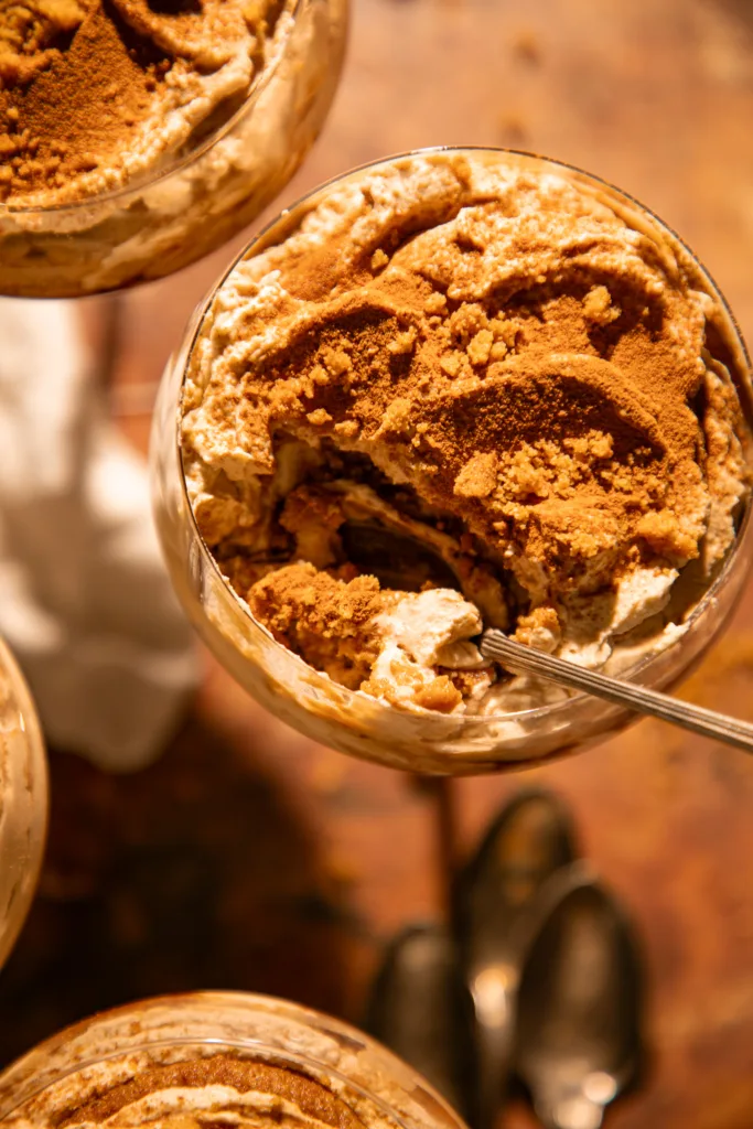 Close-up of a spoon scooping creamy gingerbread tiramisu layered with spiced mascarpone and soft gingersnaps.
