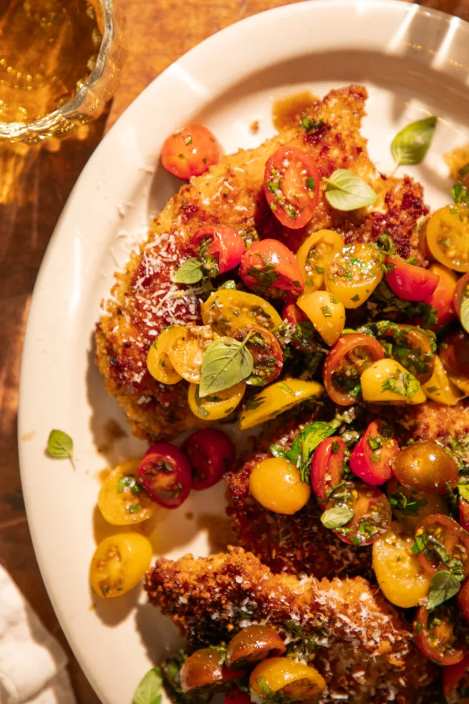 Crispy lemon herb bruschetta chicken served over a bed of orzo pasta with extra tomato herb topping, perfect for an easy Italian-inspired dinner.