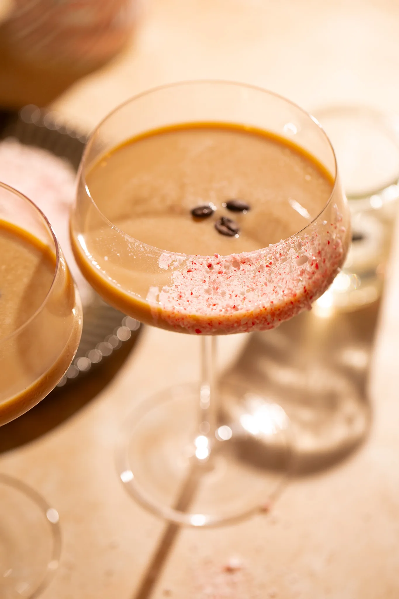 Close-up of crushed peppermint rim on a creamy espresso martini, showing festive holiday texture and sparkle.