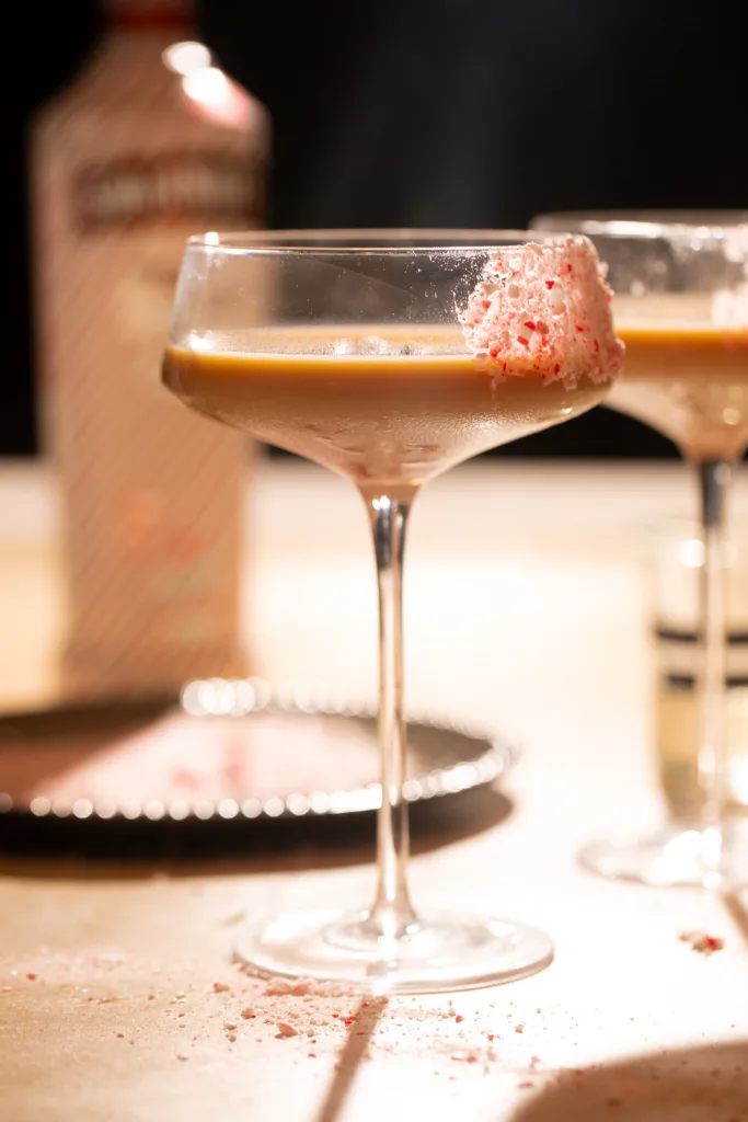 Festive peppermint espresso martini in a coupe glass with a crushed candy cane rim and creamy espresso base.