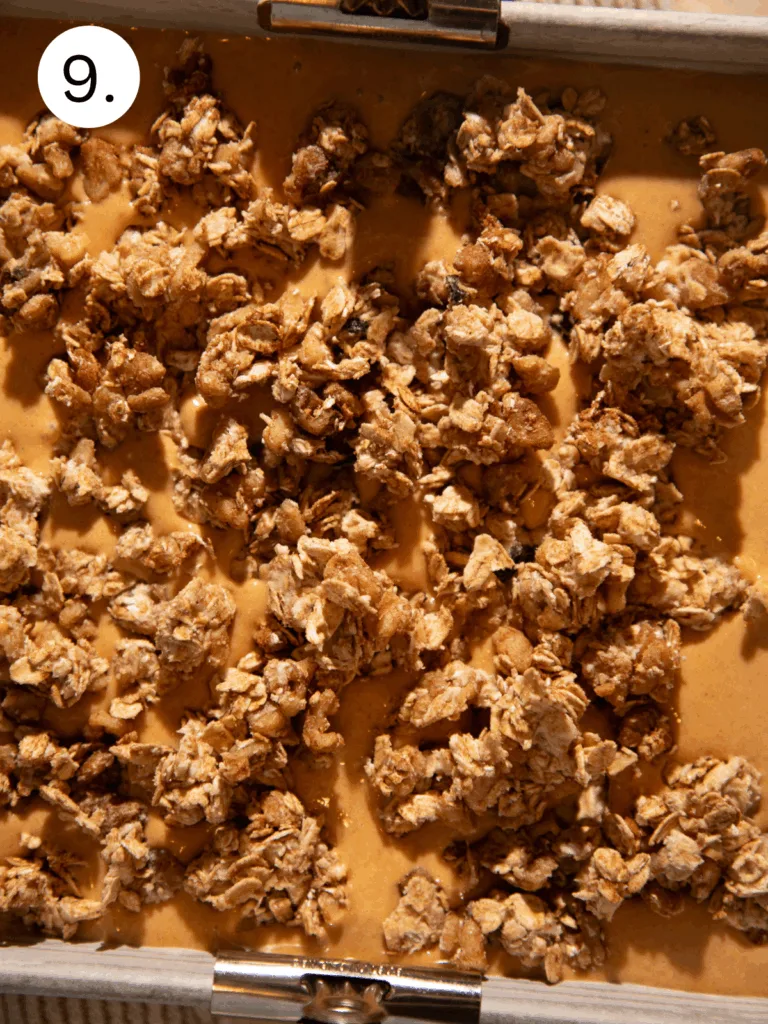 Pan of pumpkin pie filling topped with oat streusel before baking, showing golden brown clusters of oats and butter.