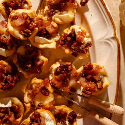 Close-up of golden crescent cups filled with melted brie, crispy bacon, and caramelized pecans.