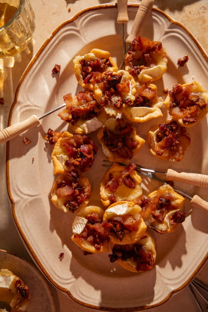 Plated maple bacon brie crescent bites on beige stoneware with cocktail forks.