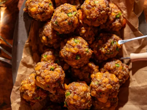 Overhead view of golden-brown jalapeño popper meatballs on a serving tray with dipping sauce.