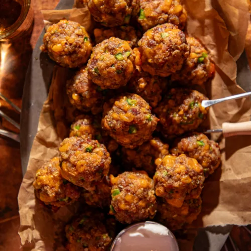 Overhead view of golden-brown jalapeño popper meatballs on a serving tray with dipping sauce.