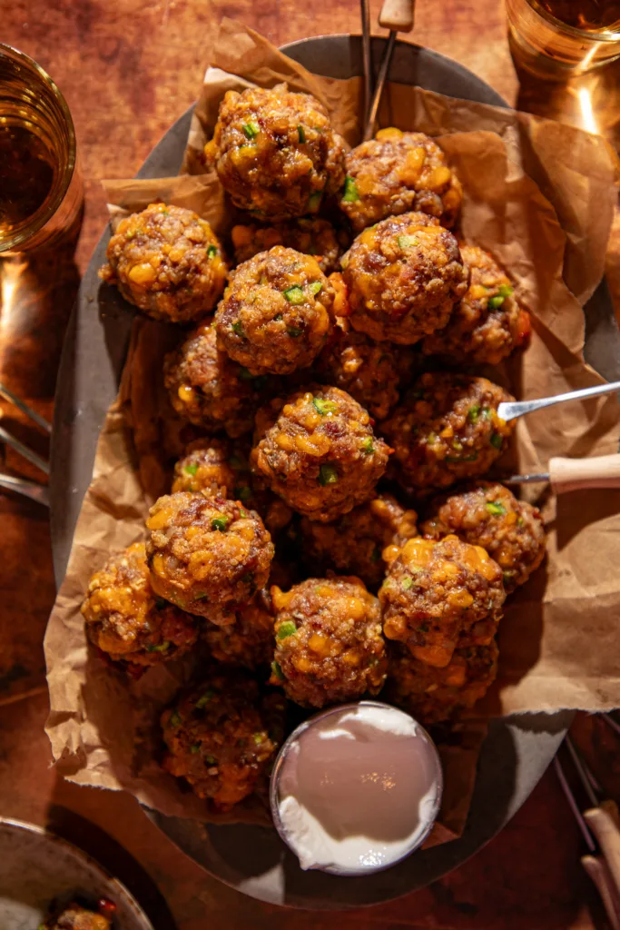 Overhead view of golden-brown jalapeño popper meatballs on a serving tray with dipping sauce.