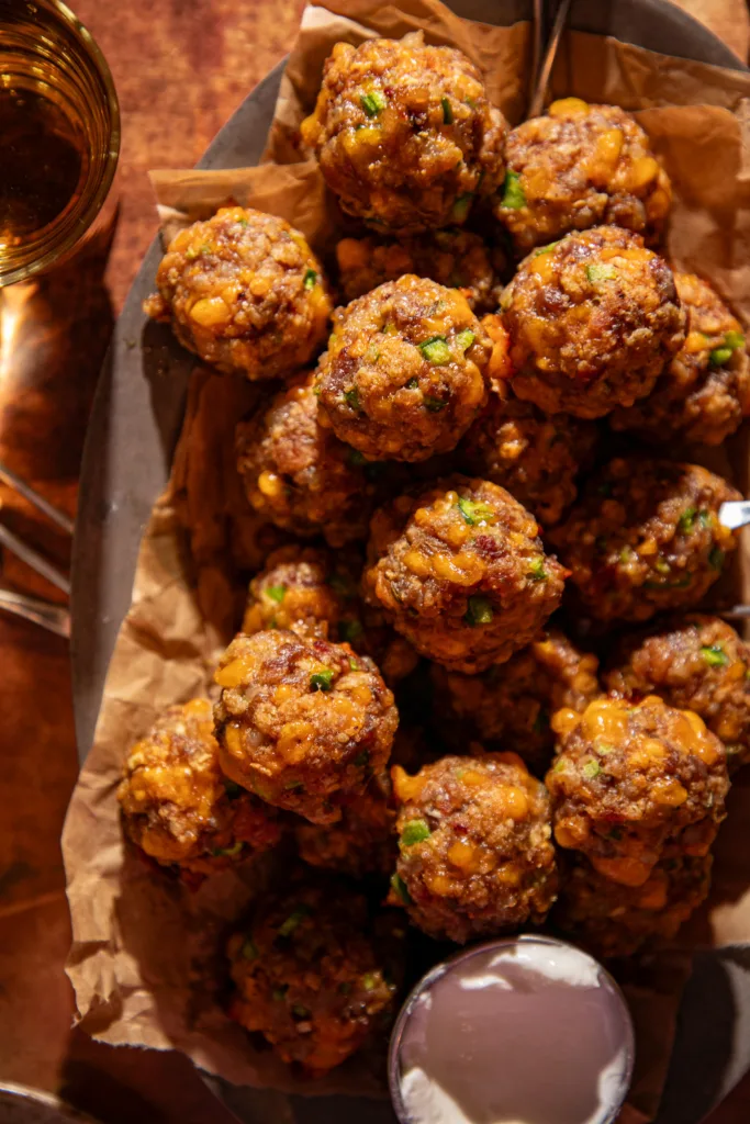 Close-up of jalapeño popper meatballs made with Italian sausage, cheddar cheese, and bacon on parchment paper.