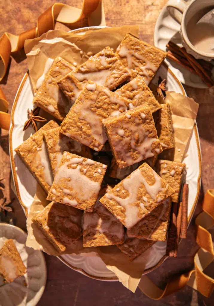 Plate of brown butter espresso gingerbread bars drizzled with a light espresso glaze, surrounded by star anise and cinnamon sticks for a cozy holiday look.