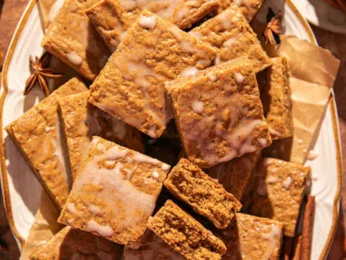 Close-up of soft gingerbread bars showing their moist texture and espresso flecks, drizzled lightly with glaze.