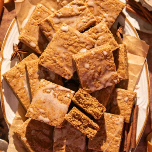 Close-up of soft gingerbread bars showing their moist texture and espresso flecks, drizzled lightly with glaze.
