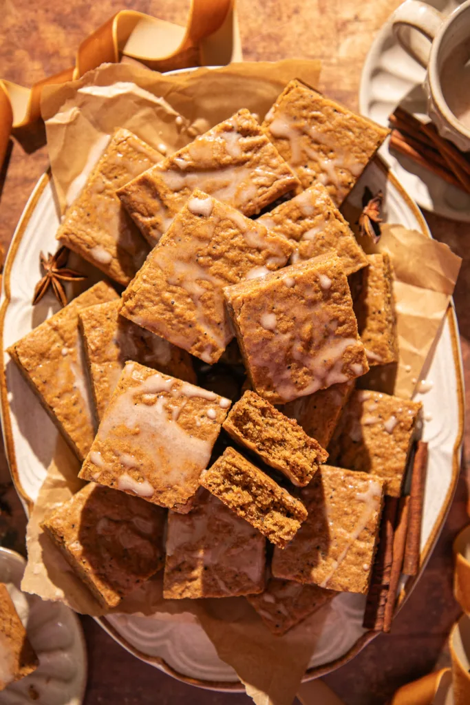 Close-up of soft gingerbread bars showing their moist texture and espresso flecks, drizzled lightly with glaze.