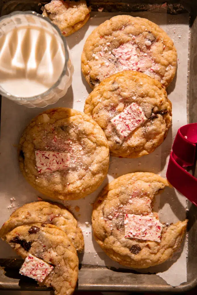 Tray of chewy peppermint bark pretzel cookies served with a glass of milk and dusted crushed peppermint.