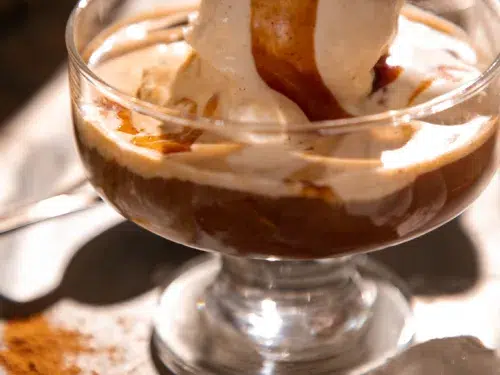 Overhead view of eggnog affogato topped with caramel beside a carton of AE Dairy eggnog and a small cup of espresso.