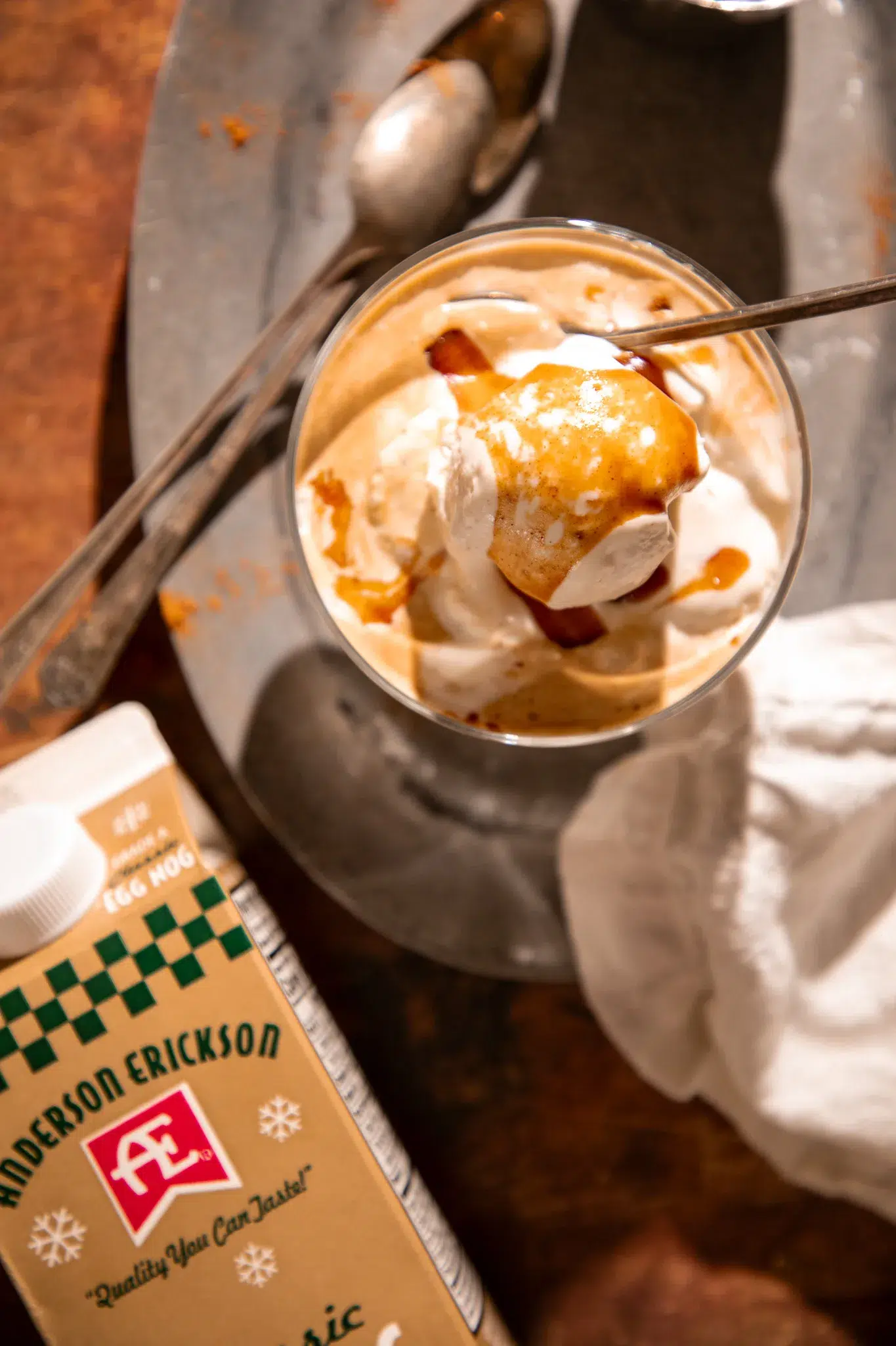 Partially melted eggnog affogato in a glass sundae dish with visible espresso and caramel swirls.