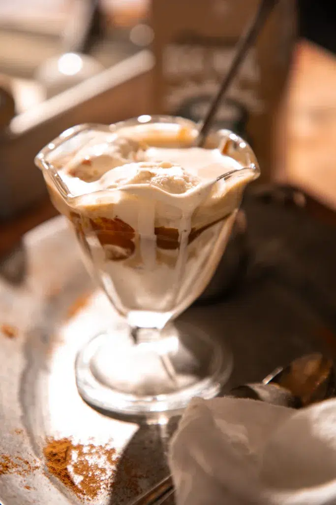 Eggnog affogato in a glass with spoon, espresso pooled at the bottom and ice cream softened on top.