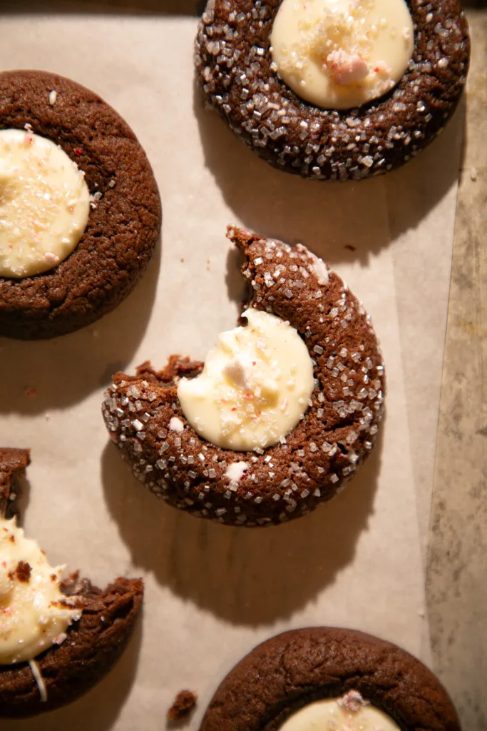 Overhead view of chocolate peppermint thumbprint cookies on a baking sheet lined with parchment paper.