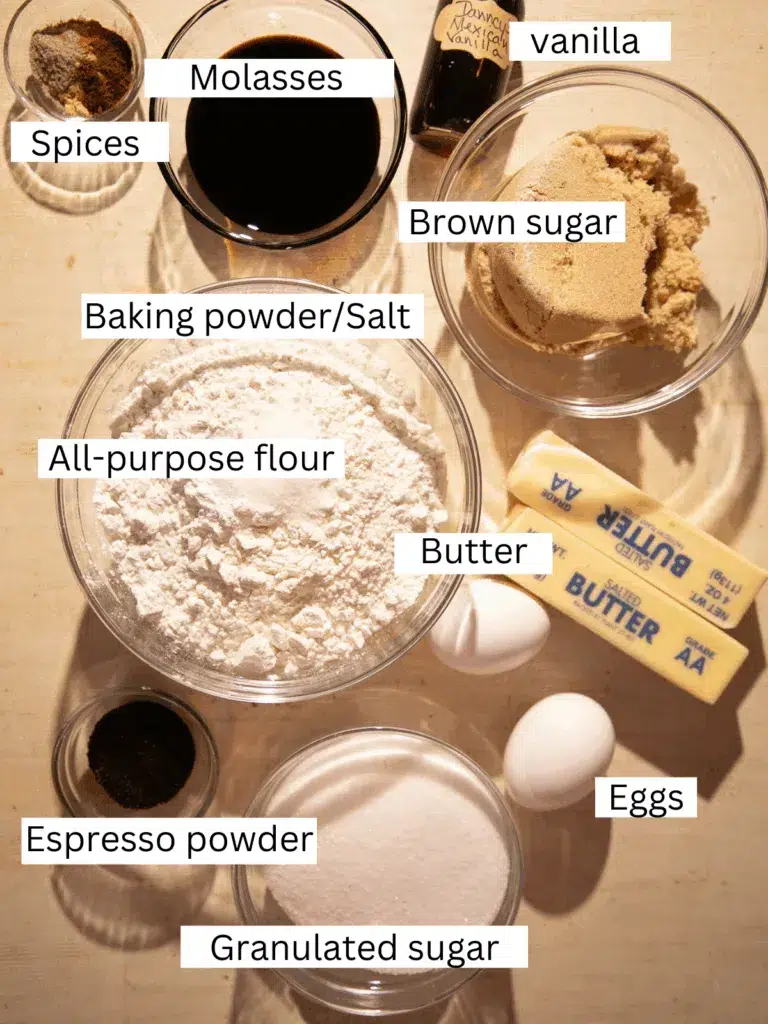 Overhead shot of labeled ingredients for brown butter espresso gingerbread bars, including flour, sugars, molasses, espresso powder, and warm spices arranged on a neutral backdrop.