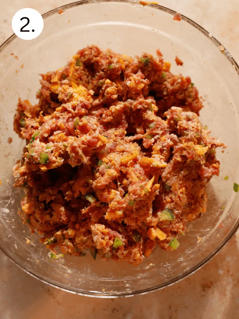 Mixed meatball filling with jalapeños, bacon, and melted cheese in a clear glass bowl.